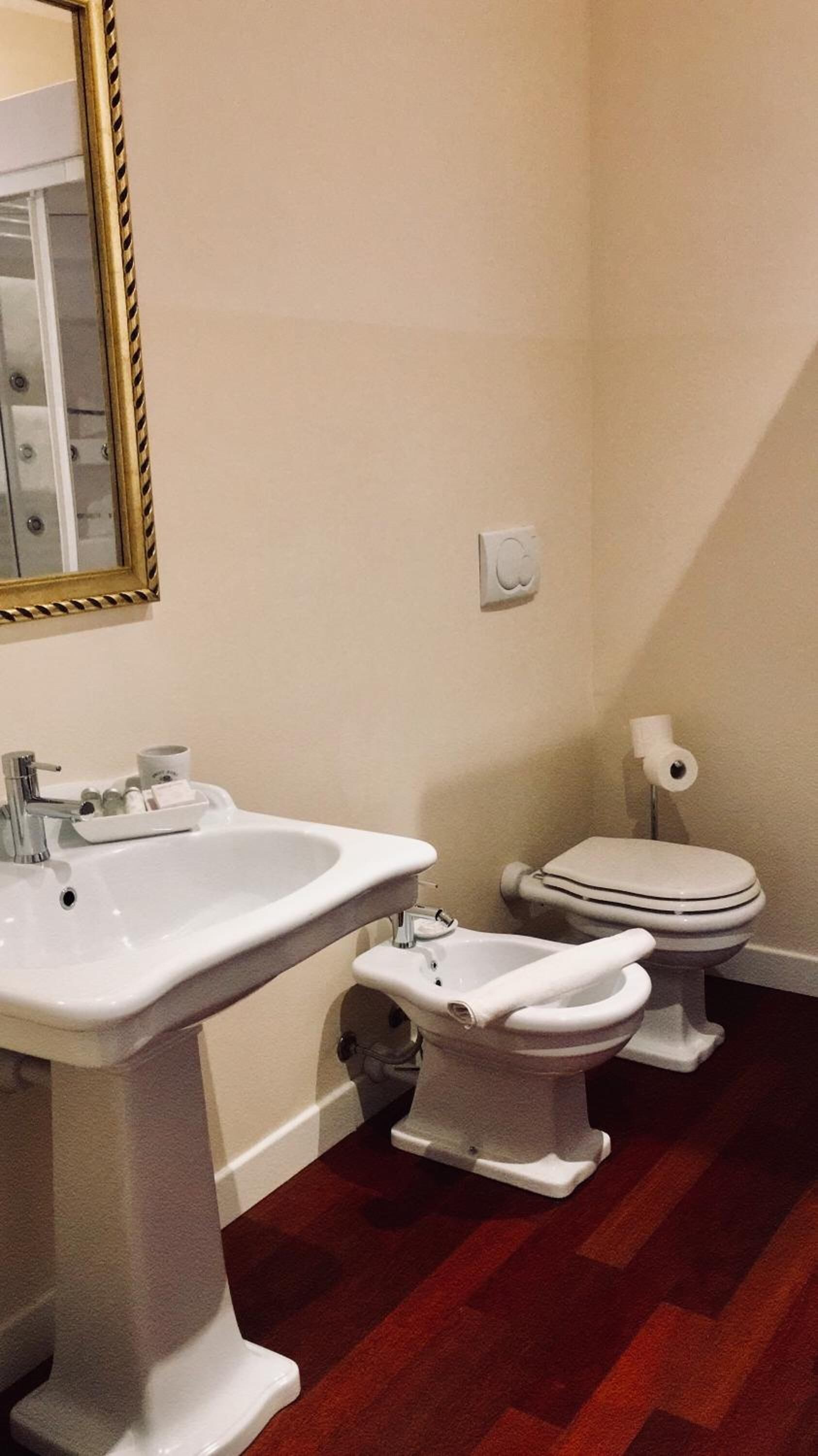 A bathroom with a pedestal sink, a bidet, and a toilet.