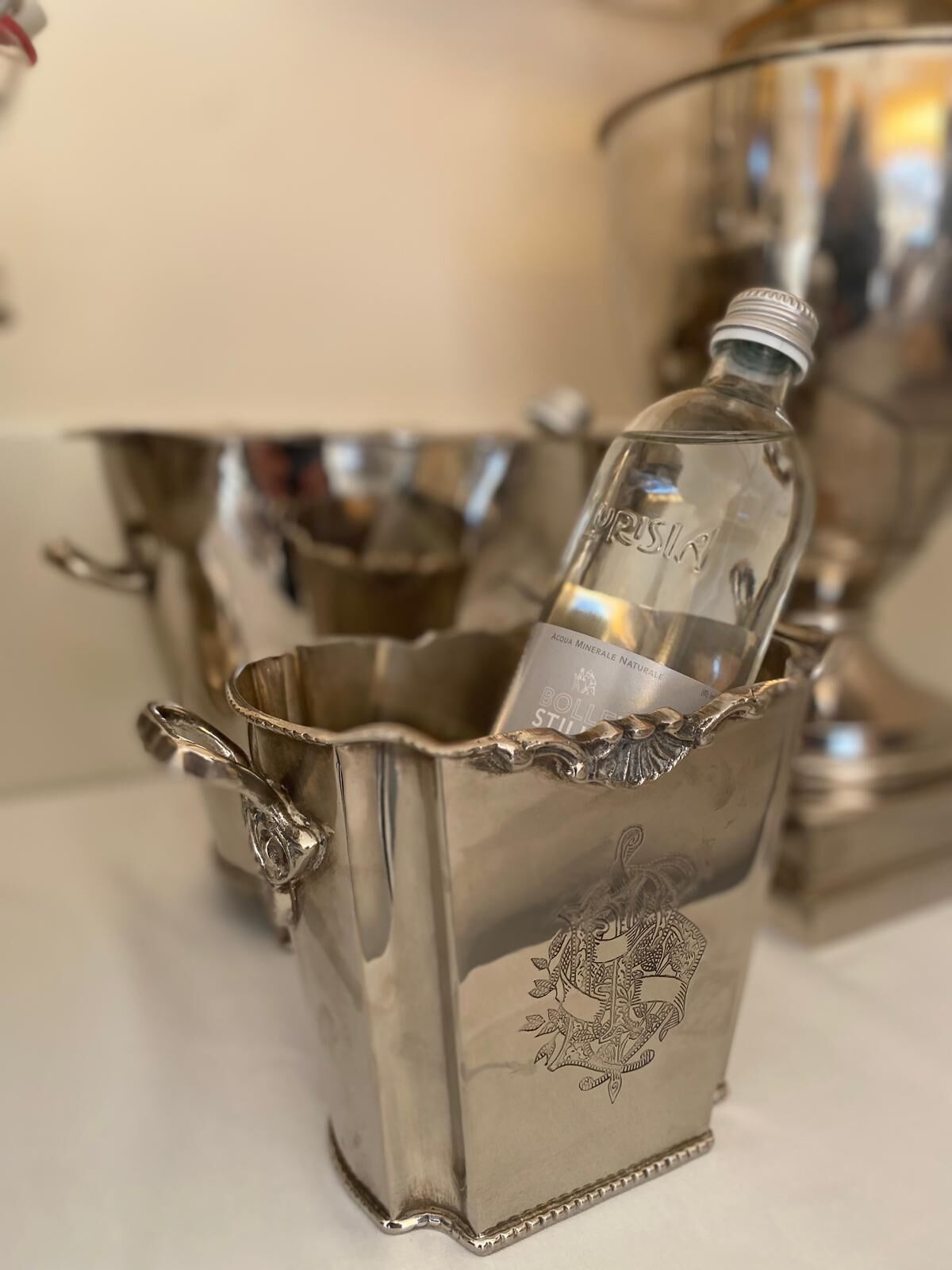 A silver bar set with a bottle of water and a glass.
