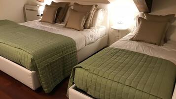Deux lits jumeaux avec des couvertures vertes, du linge de lit blanc et une poutre en bois au plafond.