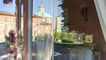 Blick aus einem Fenster auf einen Tisch für zwei Personen, eine Blumenkomposition und ein Gebäude mit Kuppel und Turm im Hintergrund.