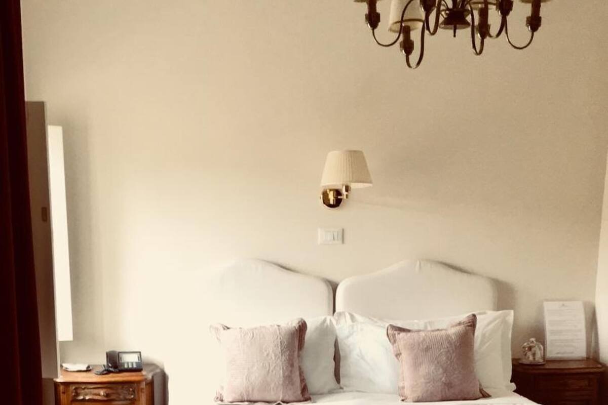 Ein Schlafzimmer mit einem großen Bett, einem Nachttisch, einer Lampe und einem Kronleuchter.