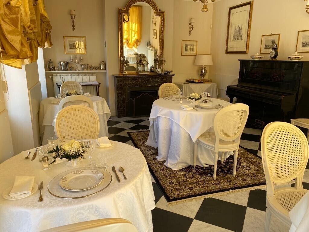 A dining room with a checkered floor, white tablecloths, and wicker chairs.