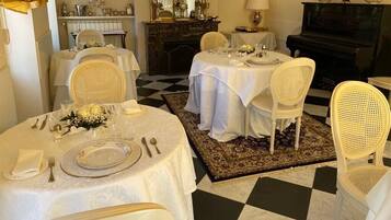 A dining room with a checkered floor, white tablecloths, and wicker chairs.
