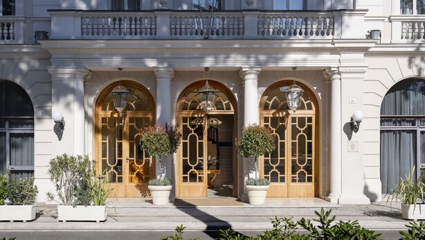 A grand entrance with three arched doors, large potted plants, and a balcony above. - Residenza Parco Fellini (Rimini)
