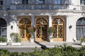 A grand entrance with three arched doors, large potted plants, and a balcony above. - Residenza Parco Fellini (Rimini)