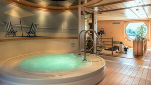 Bereich mit Whirlpool, Blick auf die Stadt, Trainingsgeräten und Streifenstuhle.