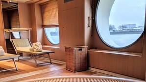Ein Wellnessbereich mit Whirlpool, Liegestühlen und Blick durch ein großes Fenster.