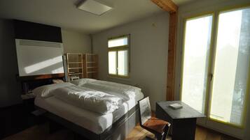 A bedroom with a bed, a desk, a window, and a wardrobe.