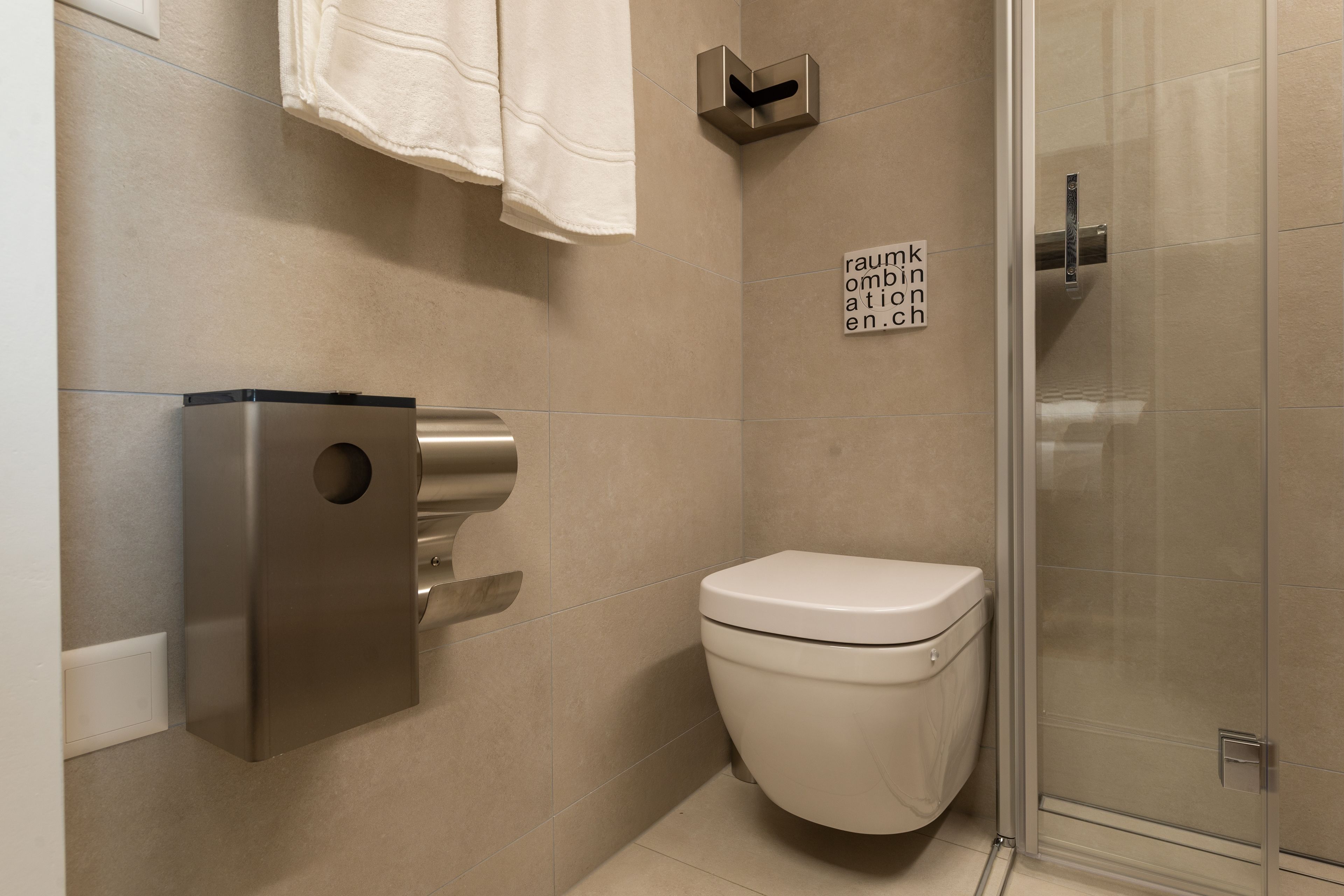Un baño moderno con inodoro, secador de manos y cabina de ducha de vidrio.