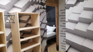 A room with a sloped ceiling, a bed, and a wooden shelving unit.