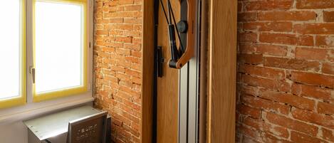 Una habitación con pared de ladrillo, puerta de madera y un escritorio con silla.