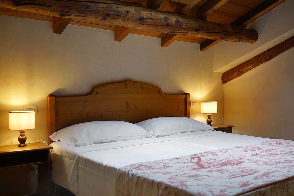 A bedroom with a wooden headboard, two bedside tables with lamps, and a bed with white bedding.
