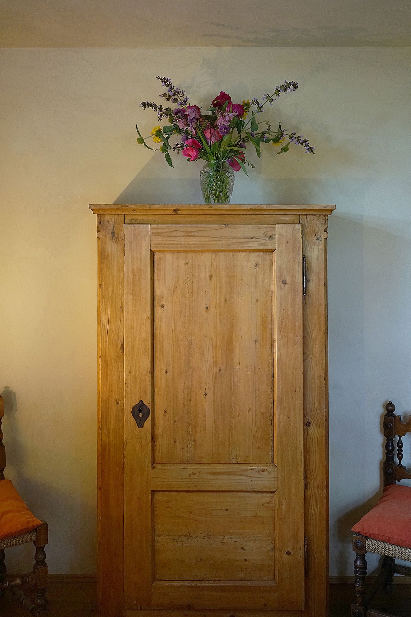 A wooden cabinet with a floral arrangement on top.
