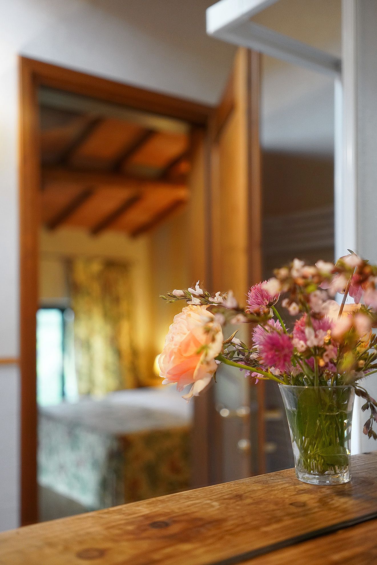 A clear view of a wooden-framed window with a vase of flowers on a wooden ledge.