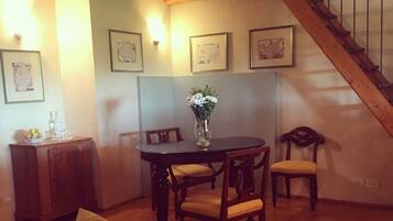 Un comedor con una mesa y sillas de madera, un jarrón con flores y una escalera que sube a un nivel superior.