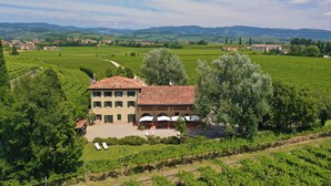 A large villa with a courtyard, surrounded by vineyards, and a view of distant hills. - Domus Cariana (San Pietro in Cariano)
