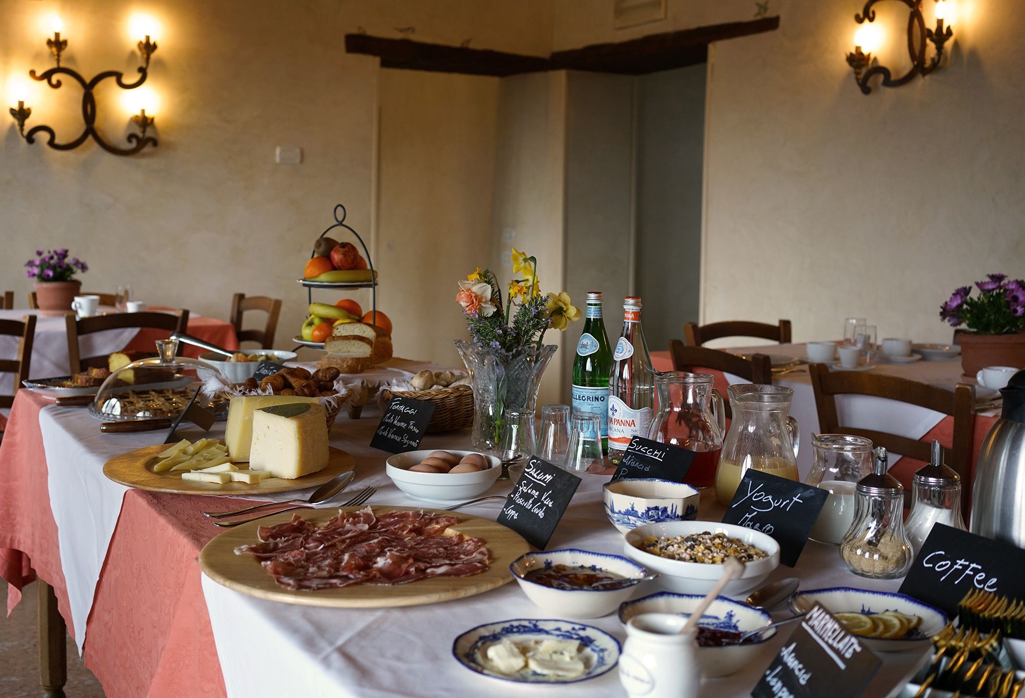 A breakfast buffet with various cheeses, meats, and pastries.