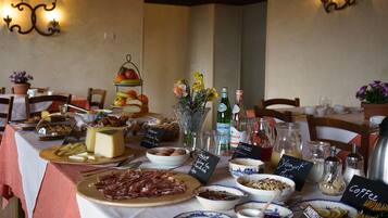 A breakfast buffet with various cheeses, meats, and pastries.