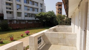 A courtyard with a tiled floor, potted plants, and a building with multiple windows and air conditioning units. - The Blue Lagoon Resort (Mawal)