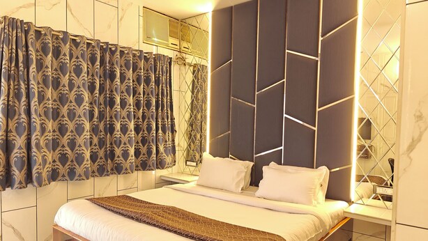 A modern bedroom with a large bed, dark patterned curtains, and a geometric headboard. - The Blue Lagoon Resort (Mawal)