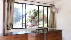 A room with a large window, a wooden cabinet, a white wall, and a ceiling fan. - The Blue Lagoon Resort (Mawal)