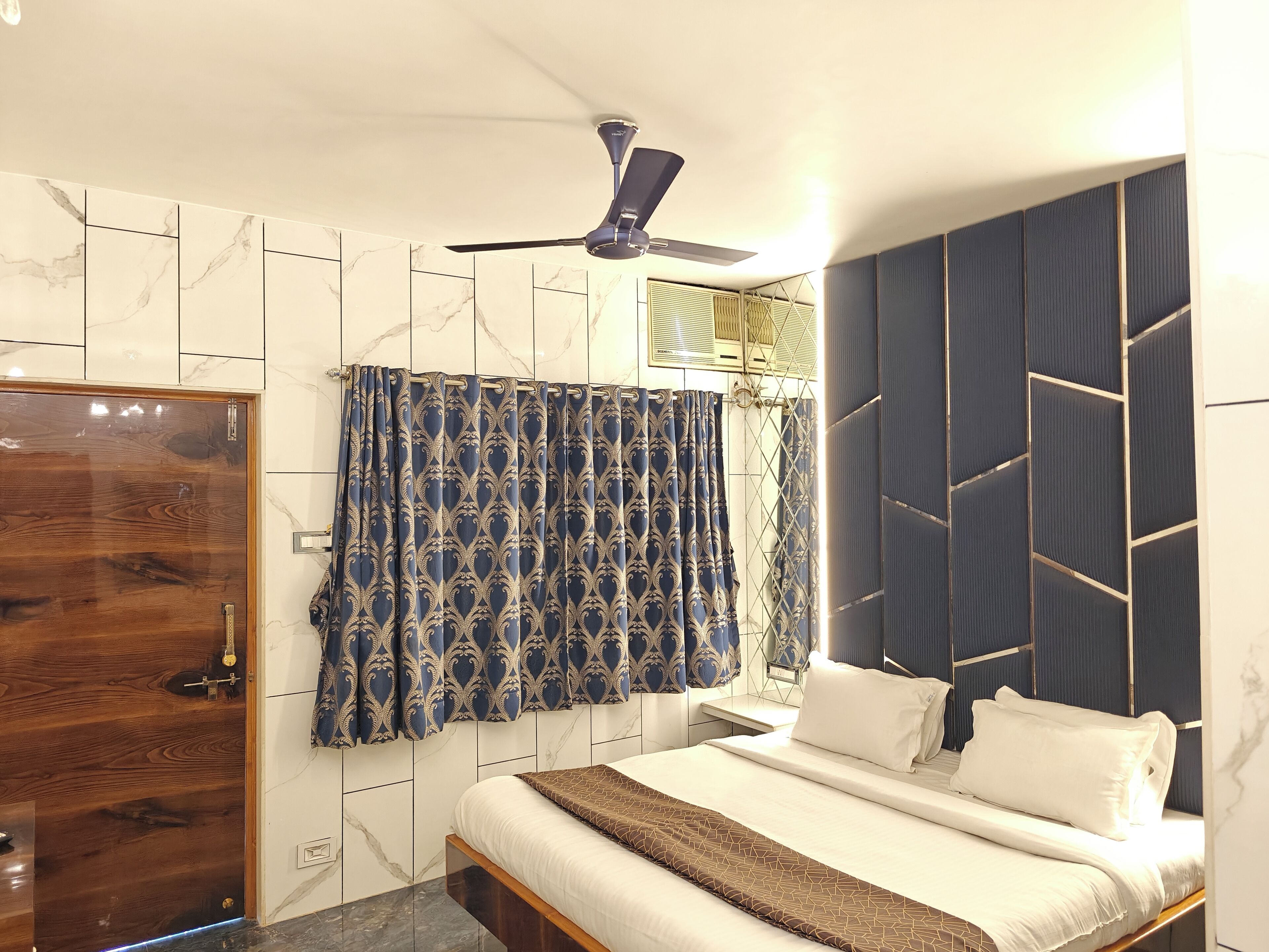 A bedroom with a bed, a ceiling fan, and a window with curtains.