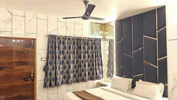 A bedroom with a bed, a ceiling fan, and a window with curtains.