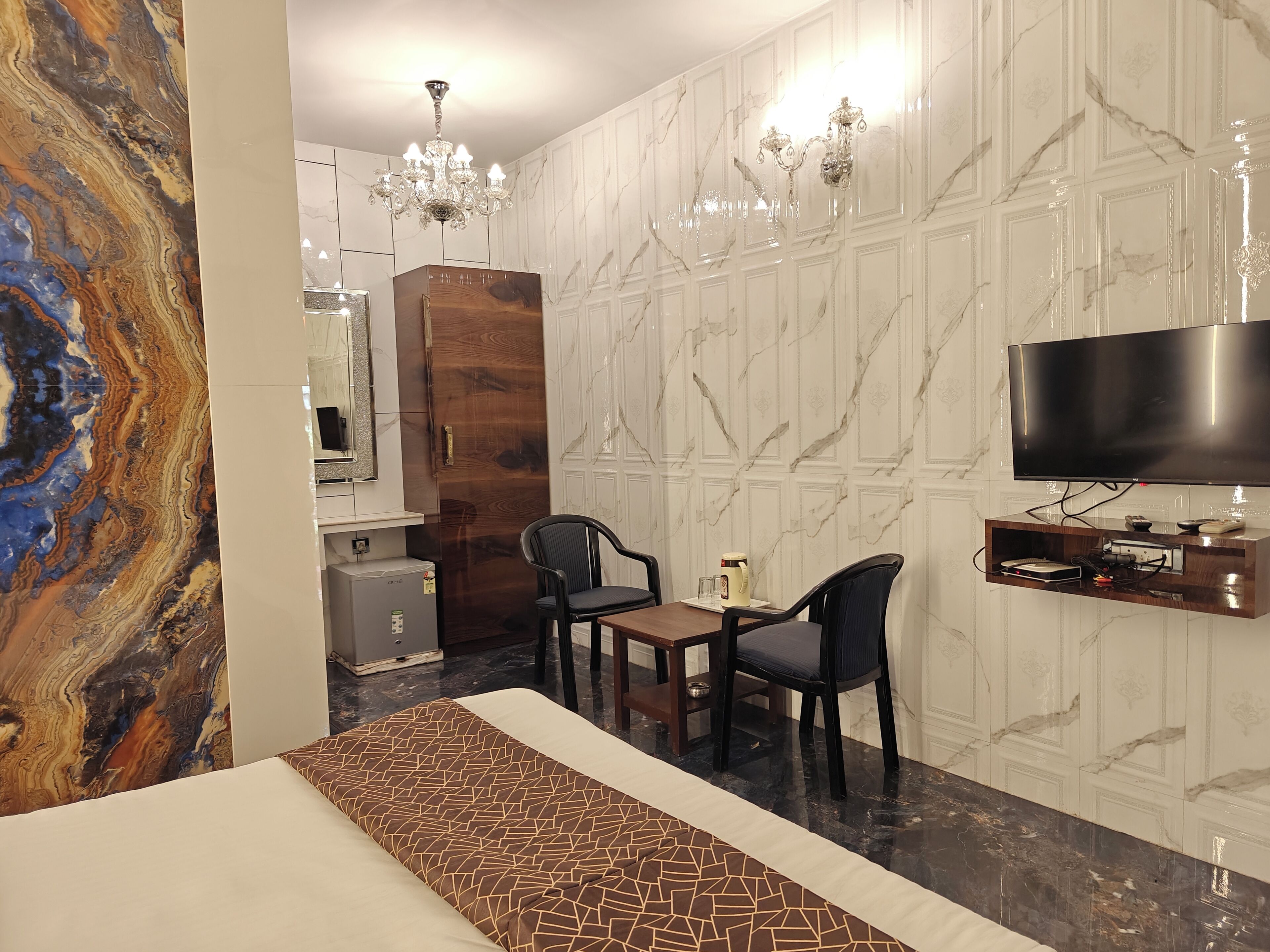 Een hotelkamer met een bed, een bureau met twee stoelen, een televisie en een minibar.