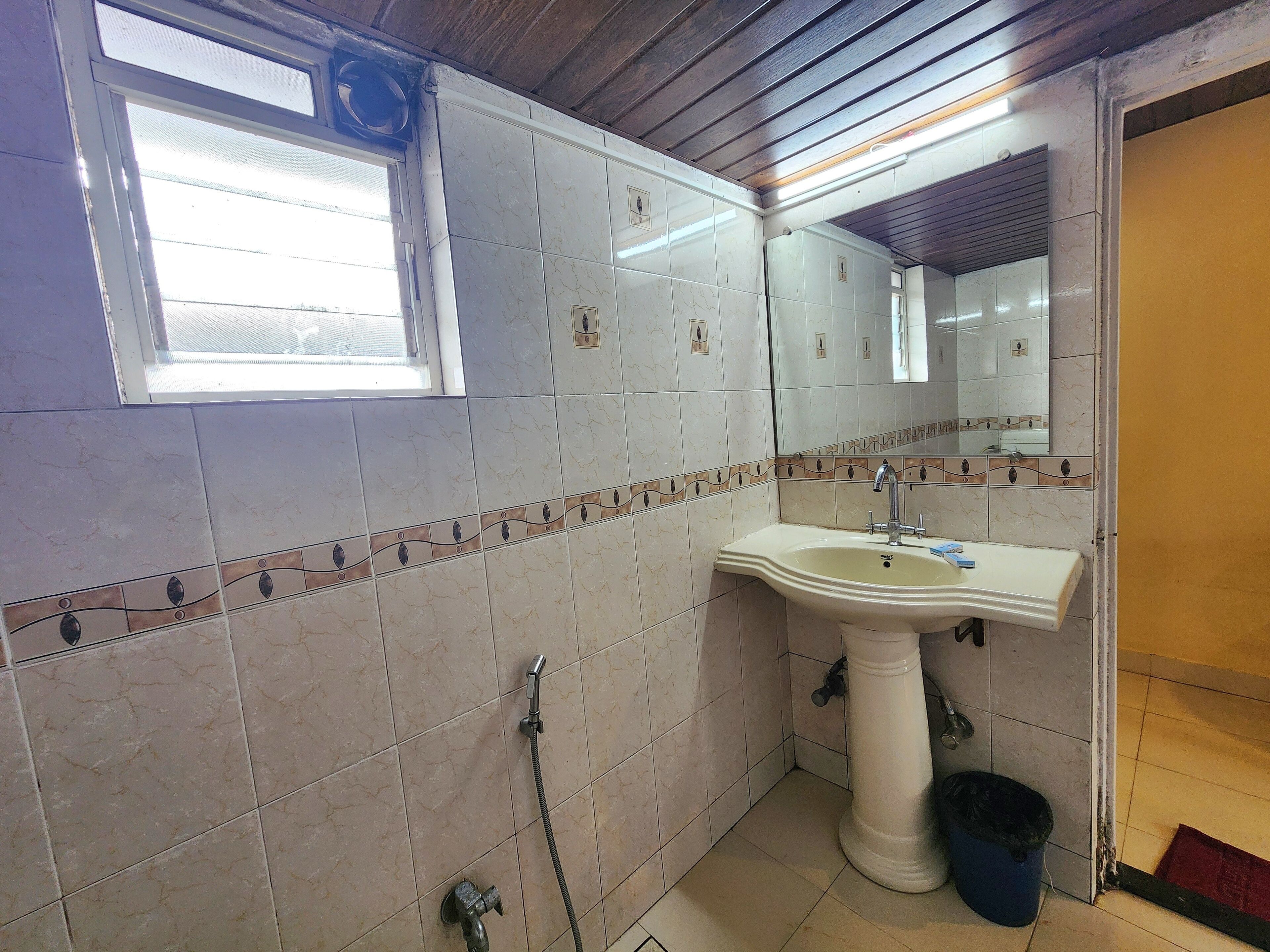 A bathroom with a sink, mirror, shower, and a window.