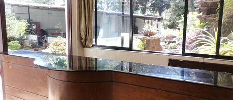 A room with a large window overlooking a garden with various plants and a rock formation.