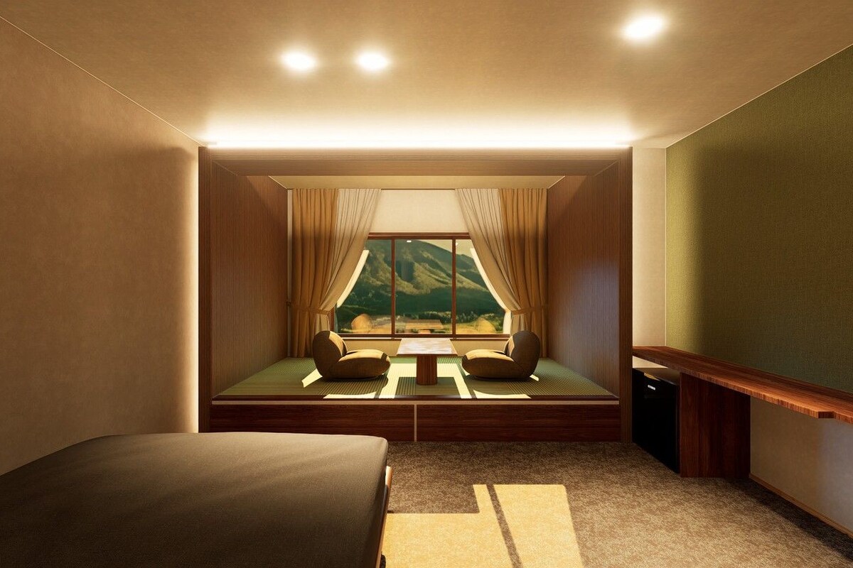 A room with a bed, a small table, a window with curtains, and a view of a mountain landscape.