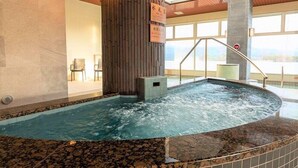 A hot tub with a wooden wall and a sign, a tiled floor, and a view of the outdoors. - Aso Kumamoto Airport Hotel Eminence (Mashiki)