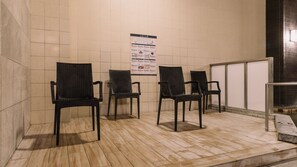 A waiting area with four black chairs and a poster on the wall. - Aso Kumamoto Airport Hotel Eminence (Mashiki)