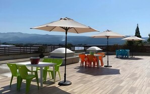 An outdoor patio with tables and chairs, umbrellas, and a view of mountains. - Aso Kumamoto Airport Hotel Eminence (Mashiki)