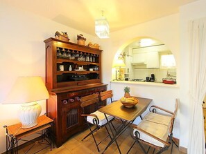 Un coin repas accueillant, avec un buffet en bois, une table et des chaises, et une fenêtre donnant sur la cuisine.