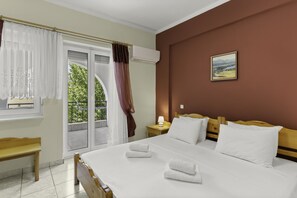 Relax in a spacious room with a large bed, wooden bench, and a wall-mounted air conditioner.