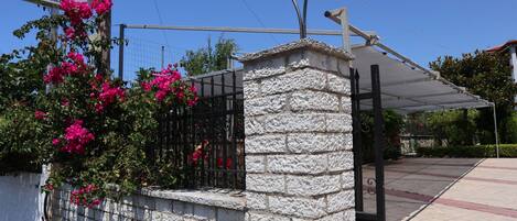 A stone wall with a metal gate, a sign for 'Delphin Apartments', and a street lamp.