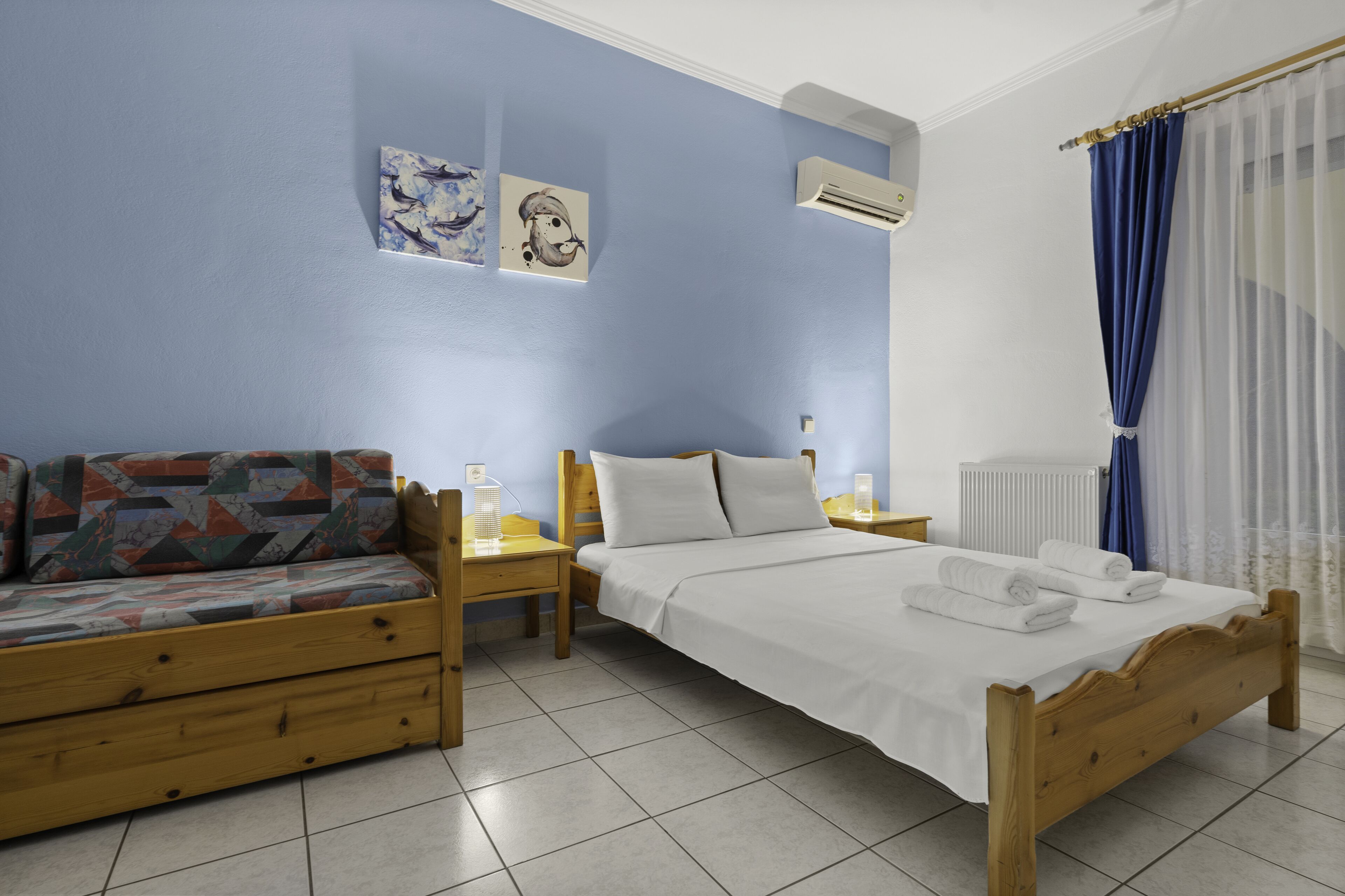 Un dormitorio con una cama, un sofá, una mesita de noche y un aire acondicionado de pared.
