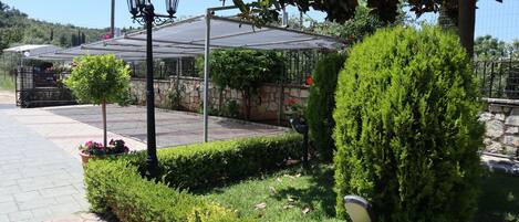 Un jardín con pérgola, muro de piedra y setos cuidados.
