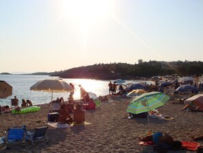 Guests can relax on the beach with comfortable chairs and towels, surrounded by umbrellas and scenic views.