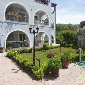 Stunning two-story building with a beautiful garden and flower-adorned balconies.