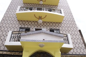 A multi-story building with balconies, a patterned facade, and a central entrance with a decorative arch. - Elu Hotel Appart (Douala)