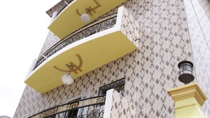 Un edificio con fachada ornamentada, balcones con toldos amarillos y barandillas de metal decorativo.