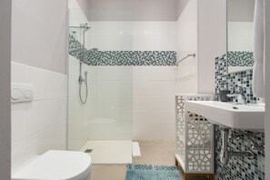 A modern bathroom with a glass-enclosed shower, a white toilet, and a sink with a decorative tile backsplash. - 39 Loader (Cape Town)