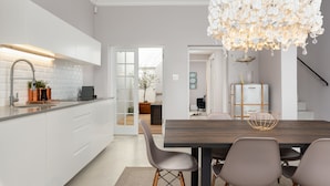 Una cocina moderna con armarios blancos, una mesa de comedor de madera oscura y una lámpara de flores blanca y original.