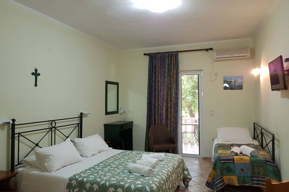 A bedroom with a bed, a chair, a desk, and a window with curtains.