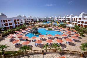 A resort with a central pool, multiple levels of balconies, and sun loungers with umbrellas. - Naama Waves Hotel (Sharm El Sheikh)