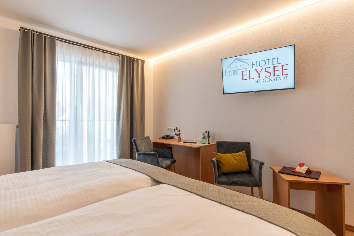 A hotel room with a bed, two chairs, a desk, and a small table.
