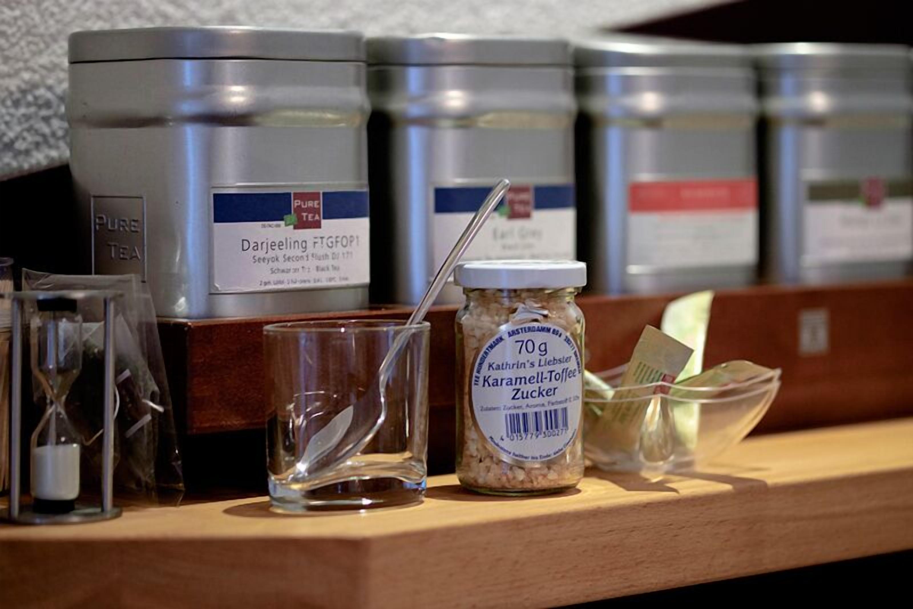 A shelf with various containers, including a jar labeled 'Kathrin's Liebster Karamel-Toffee Zucker' and a glass with a spoon.