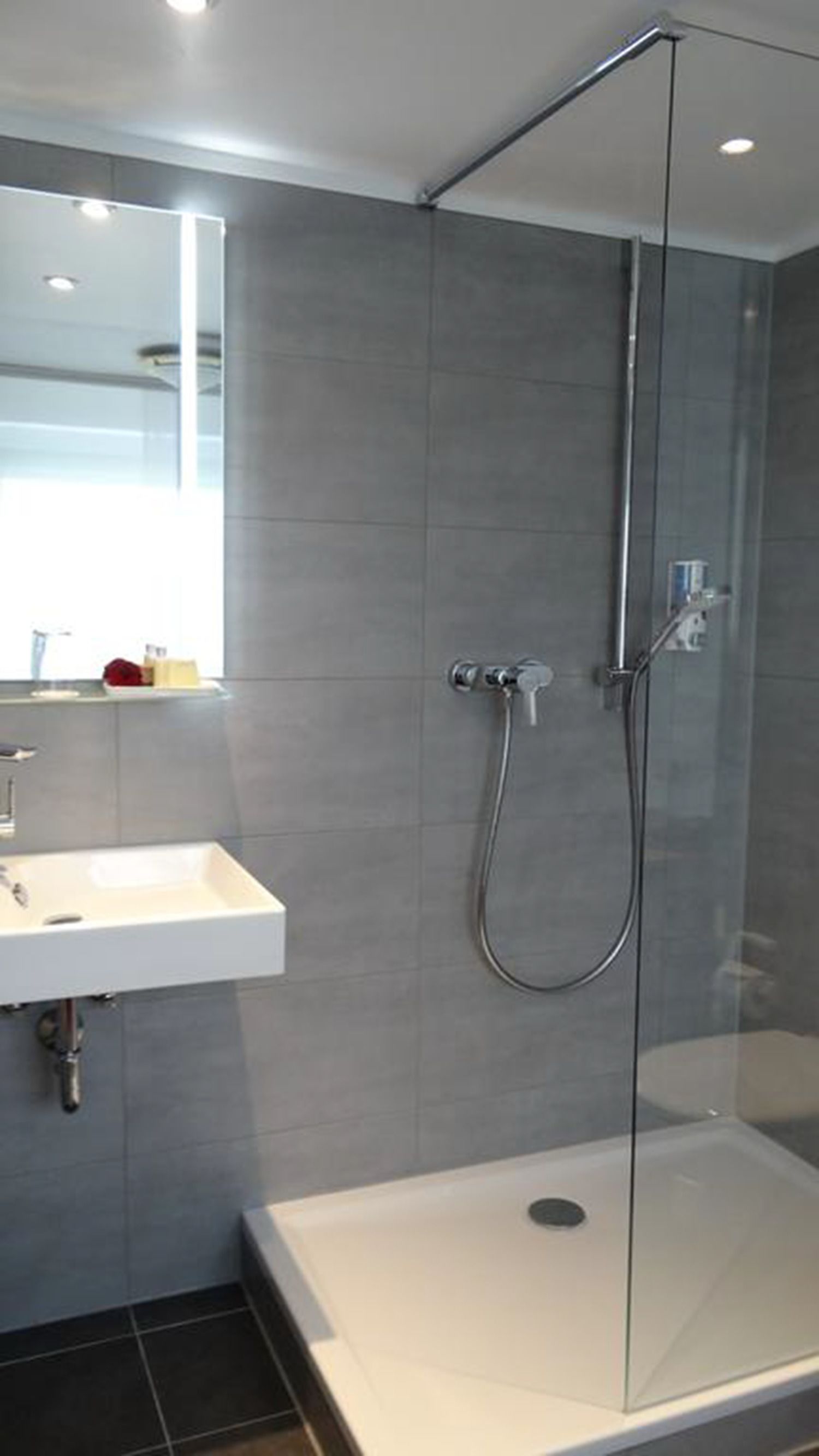 Un bagno moderno con cabina doccia in vetro, lavabo bianco e specchio sopra il lavabo.